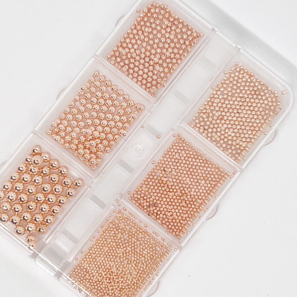 Rose Gold Metal Balls (Caviar) for Nail Art - Aerial View on White Background.