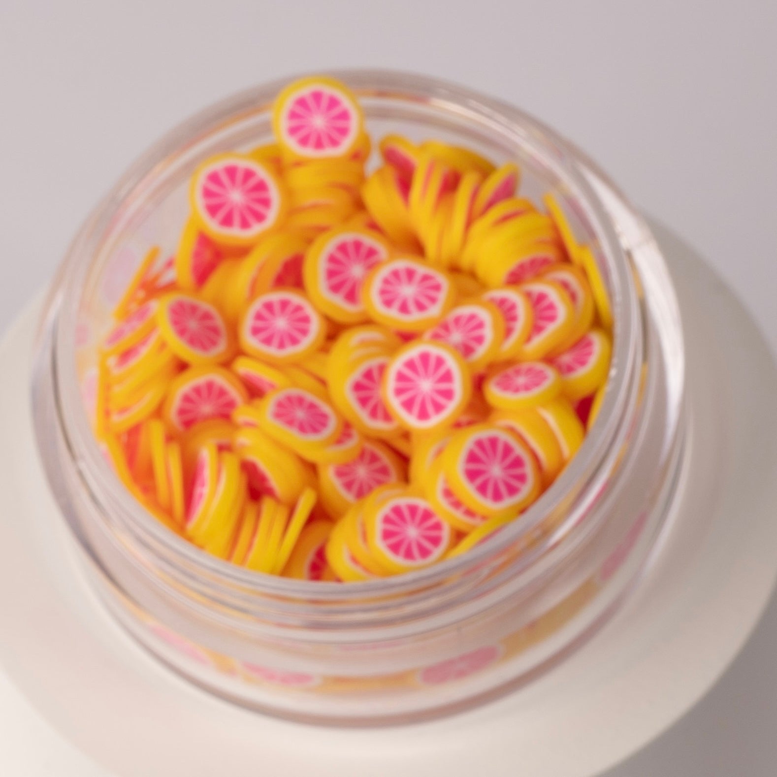 Mini grapefruit slices in clear jar on white background.