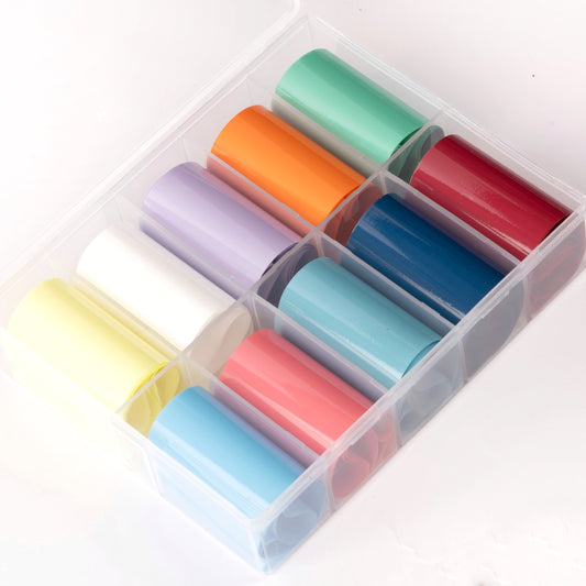 Multicolor rolls of transfer foil in clear case on white background.