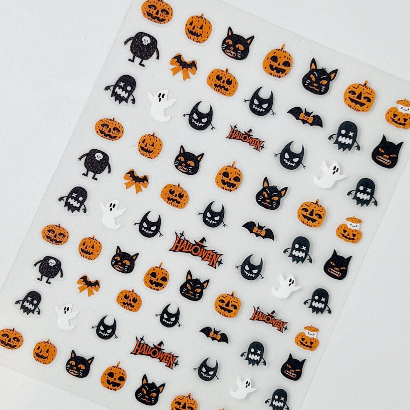 Trick or Treat Nail Stickers - Halloween-Themed Nail Stickers with Ghosts, Bats, Pumpkins, and Cats in Black and Orange Colors, Displayed on a White Background.