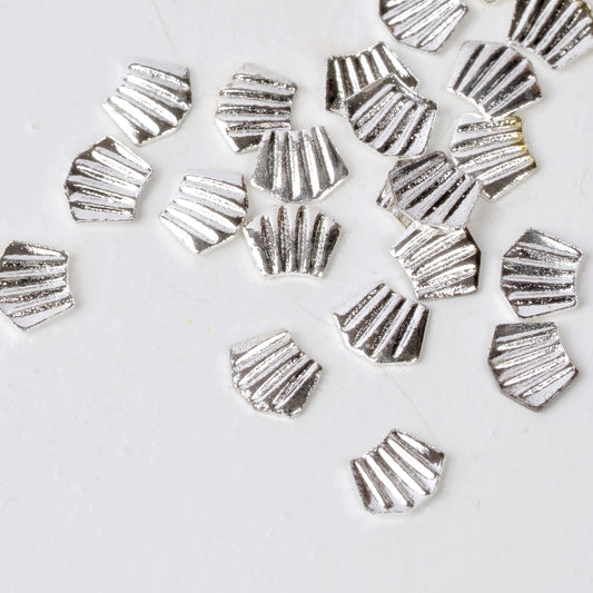 Silver nail charms scattered on white background.