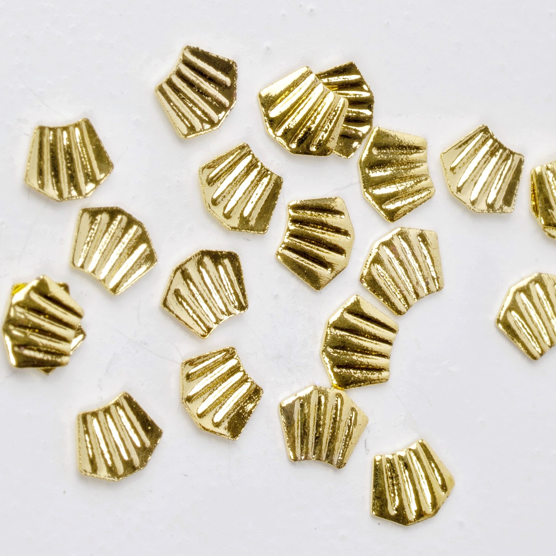 Gold nail charms scattered on white background.