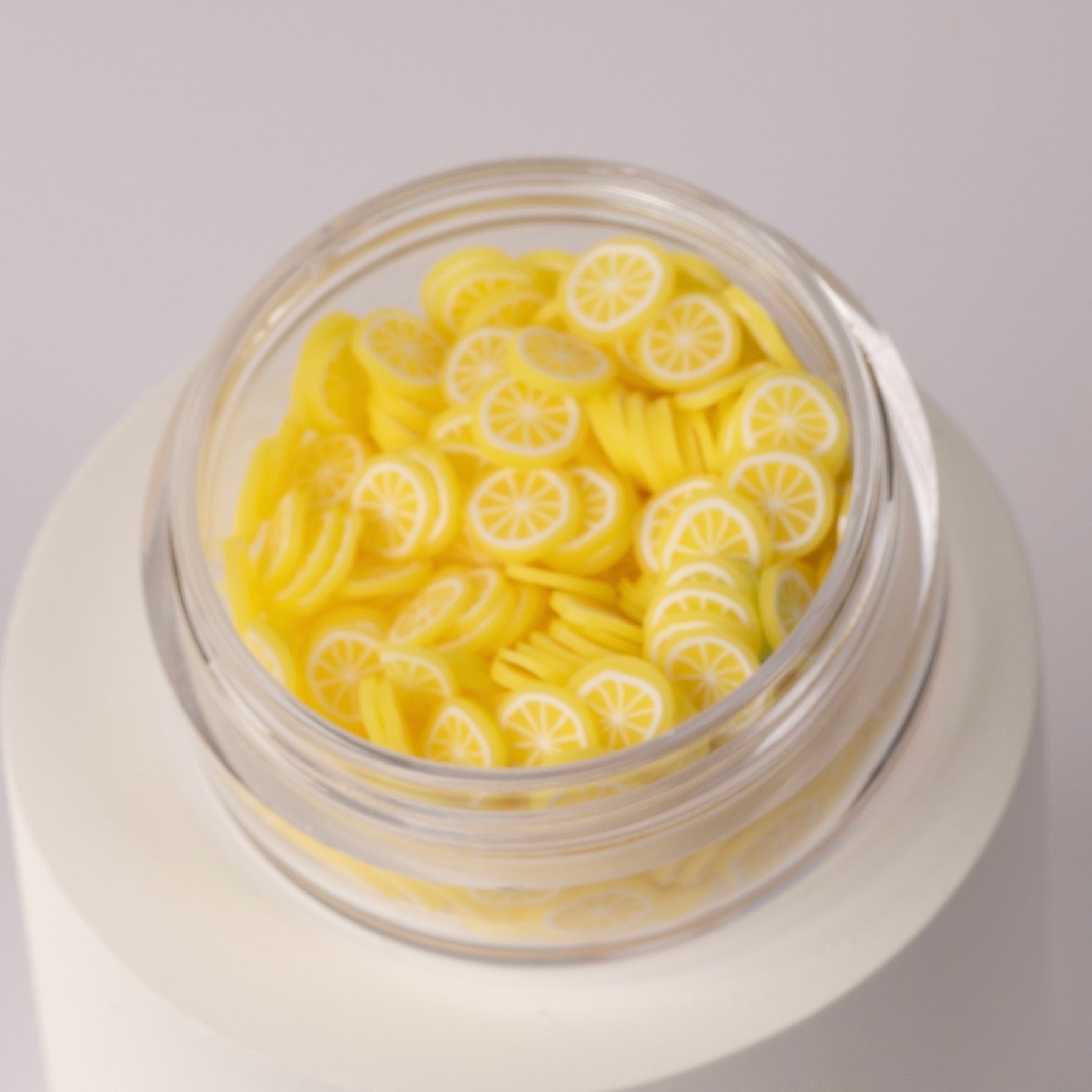 Mini lemon slices in clear jar on white background.