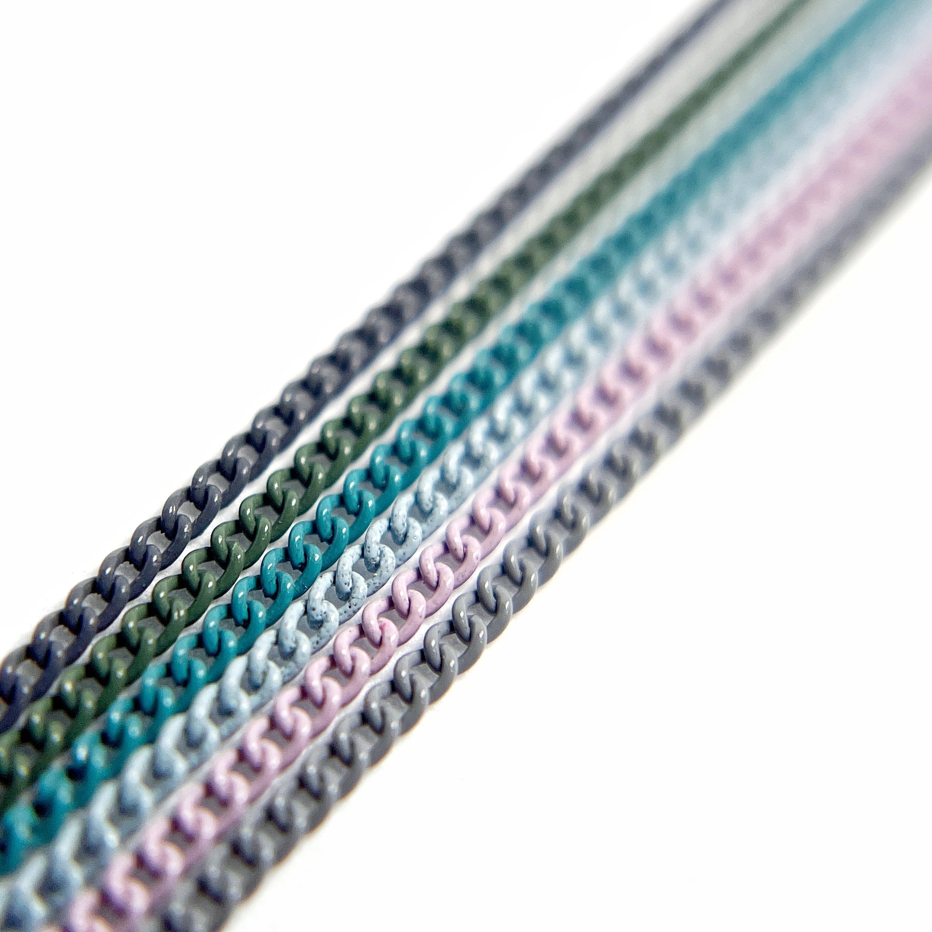 Close-Up of Multi-Color Nail Art Chains in cool blue, green and purple tones on White Background.