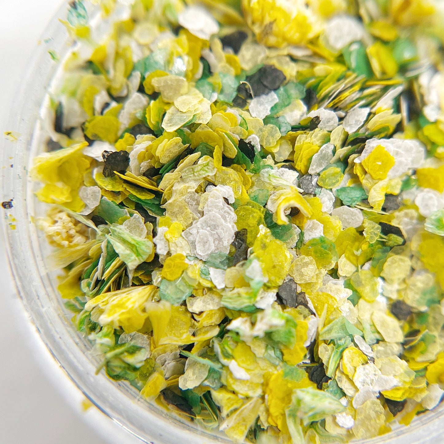 Confetti Crush Collection in Clover Crush - Colorful Mix of Mica Speckles and Dried Flower Petals in Jar, Featuring Yellow, Green, White, and Black Colors.