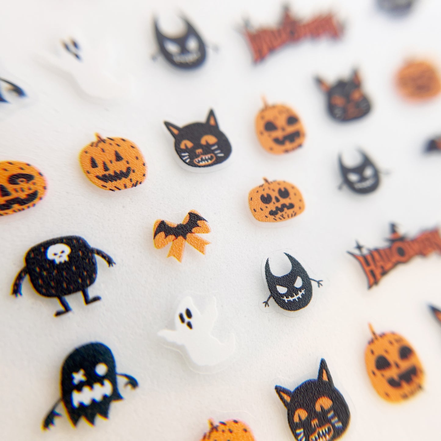 Trick or Treat Nail Stickers - Halloween-Themed Nail Stickers with Ghosts, Bats, Pumpkins, and Cats in Black and Orange Colors, Displayed on a White Background.