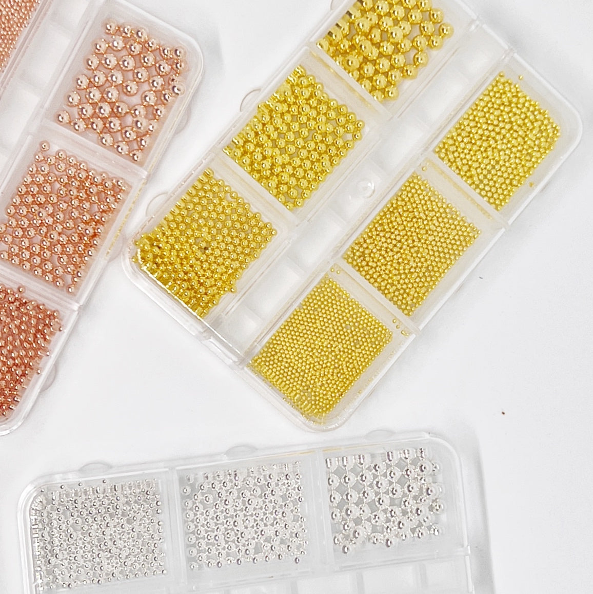 Metal Balls (Caviar) - Assortment of Small to Large Sizes in Gold, Rose Gold, and Silver, Displayed from Above in a Clear Case on a White Background.