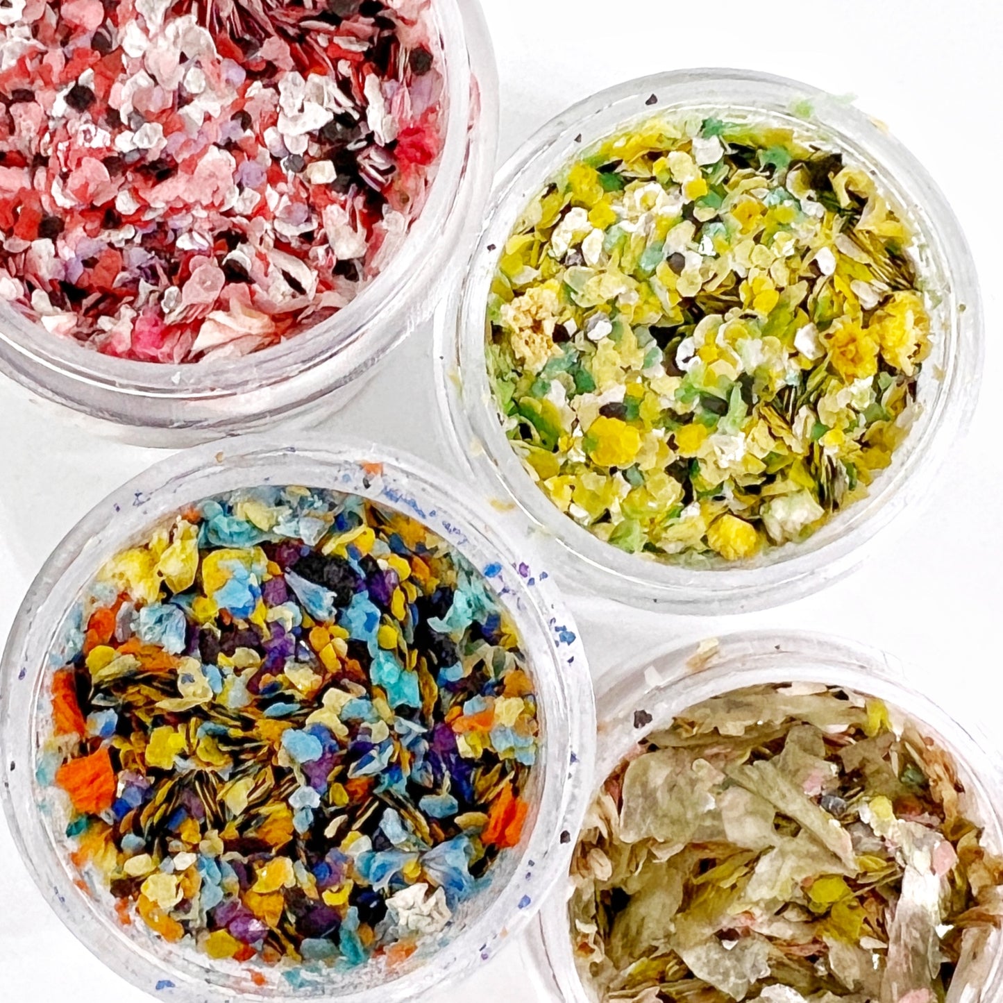 Confetti Collection - Colorful Mix of Mica Speckles and Dried Flower Petals in Jars, Ideal for Creating Unique Looks, Pictured from Above on White Background.