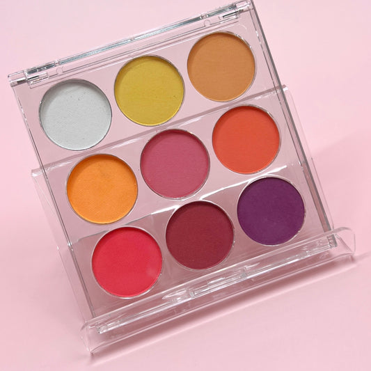 Multicolor pigment palette in clear case on pink background. 