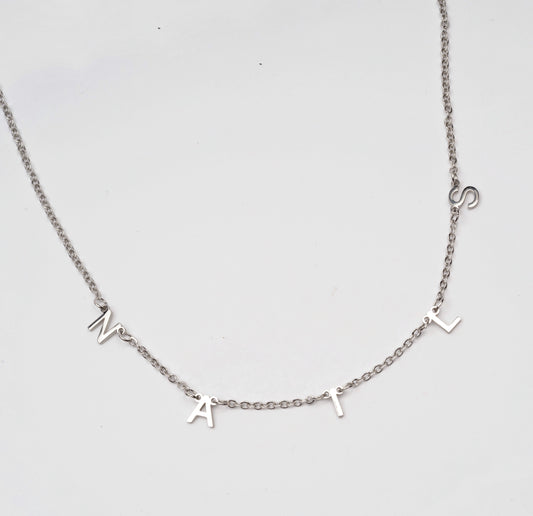 Silver chain necklace with letter charms on white backgorund. 