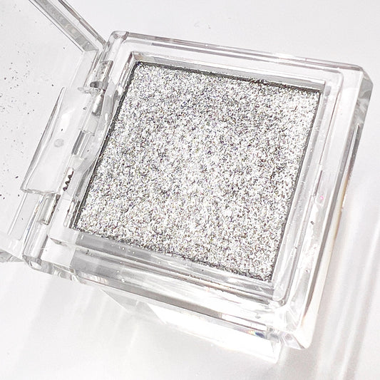 Detail view of  compact with metallic powder on white background. 
