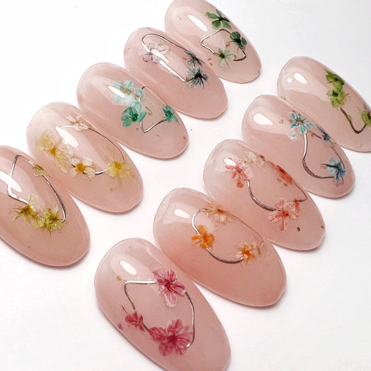 Petite Bloom Collection on 10 Nail Art Tips - Light Peach Base with Silver Details and Gel-Encapsulated Multi-Color Flowers, Displayed on White Background."