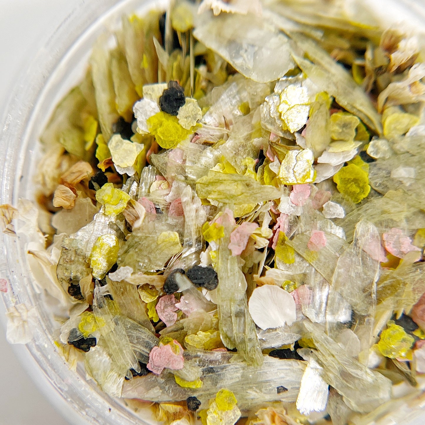 Confetti Crush Collection in Lily Crush - Colorful Mix of Mica Speckles and Dried Flower Petals in Jar, Featuring Pale Green, White, Pink, and Black Colors on White Background. 