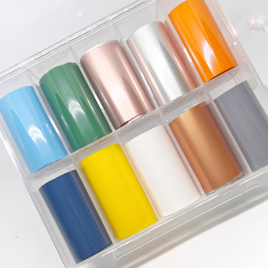 Metal and Gloss Foil Set - Assortment of Solid Gloss and Matte Metallic Transfer Foils in a 10-Grid Clear Case. Foil Colors: Light Blue, Dark Blue, Yellow, White, Green, Orange, Gray, Matte Metallic Silver, Matte Metallic Rose Gold, and Matte Metallic Copper."