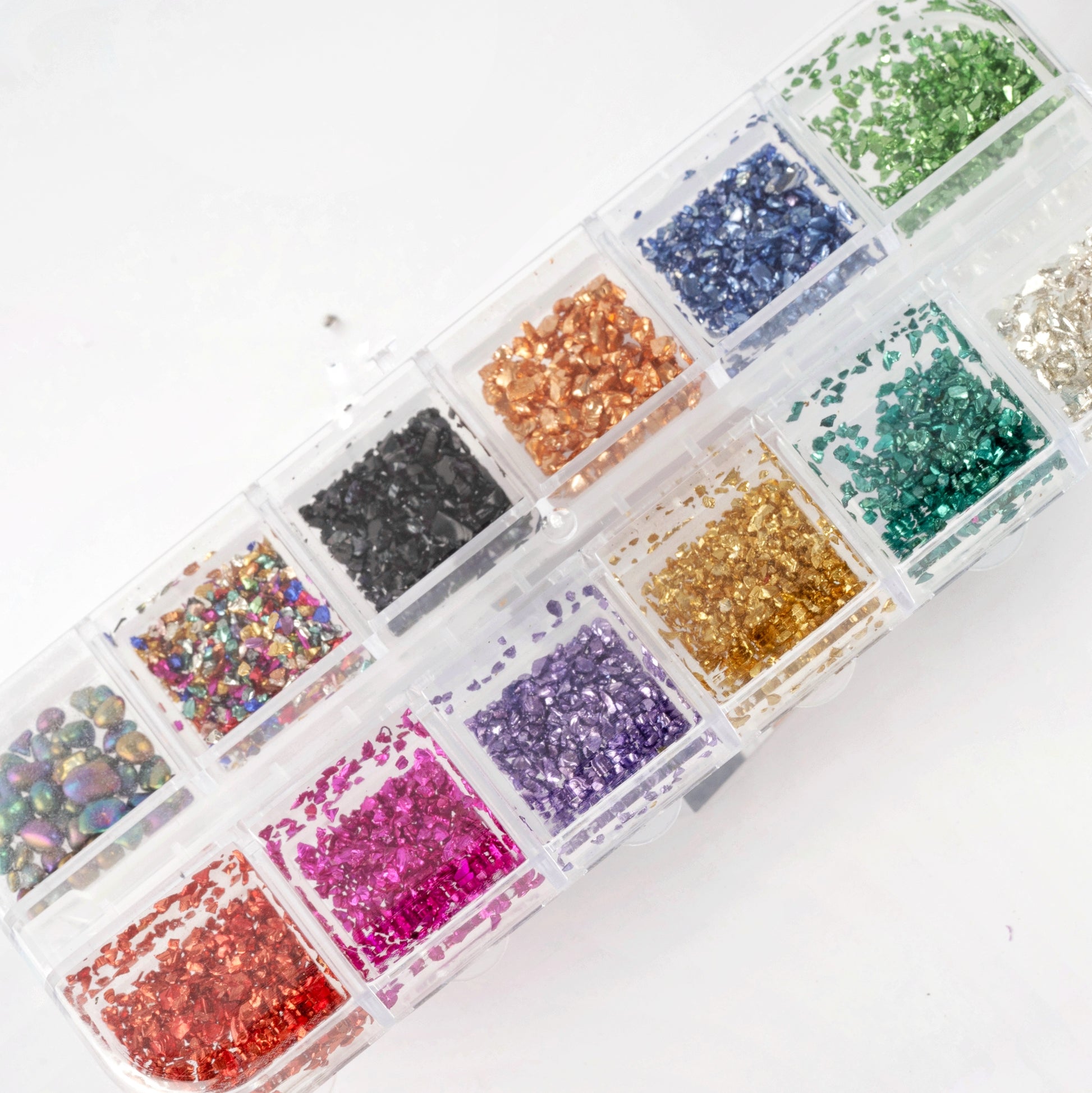 Overhead view of multi-color Metallic Pebble set in clear 12-grid storage box on white background.
