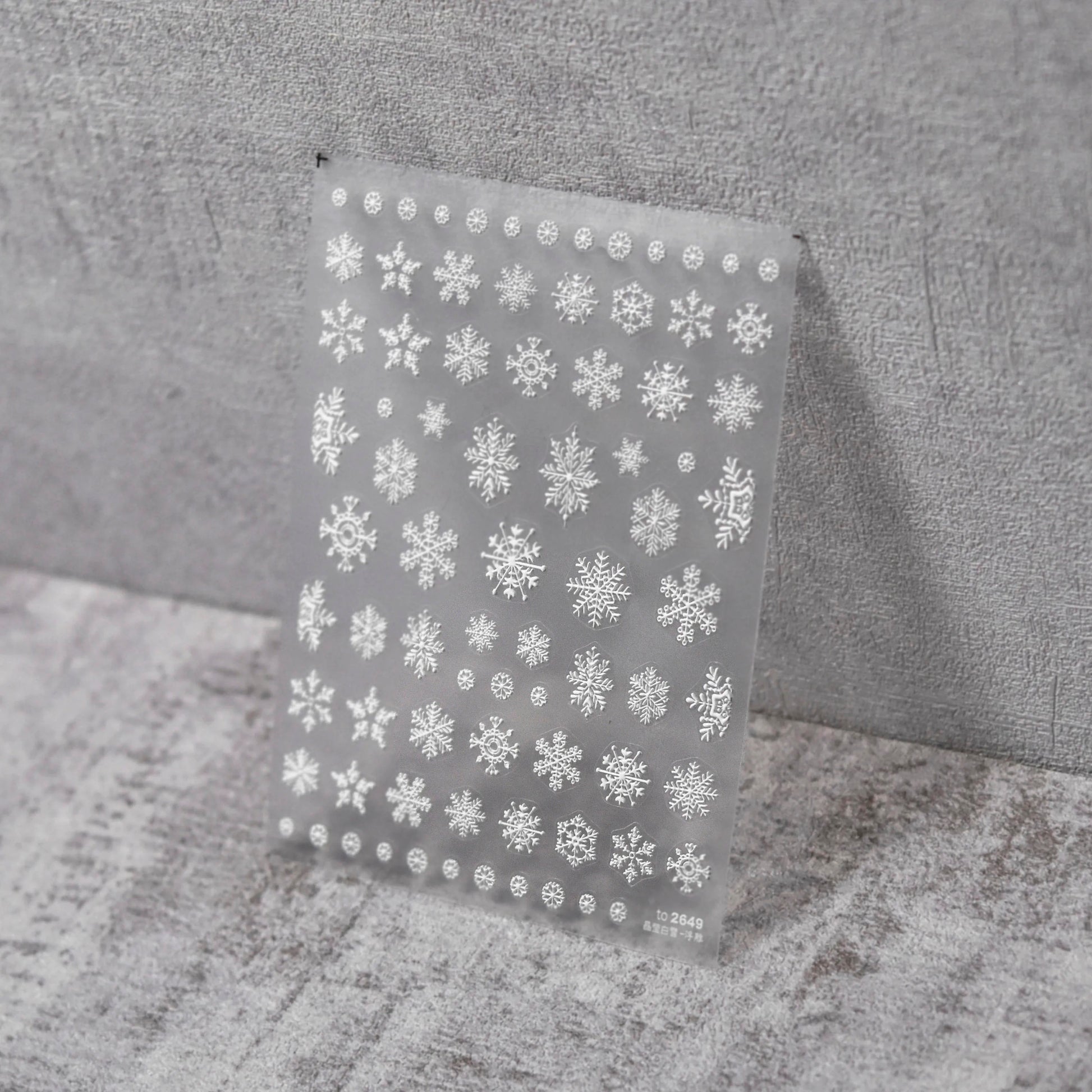 Snowflake Nail Stickers - Raised Texture White Snowflake Nail Stickers on Clear Sheet, Gray Textured Background