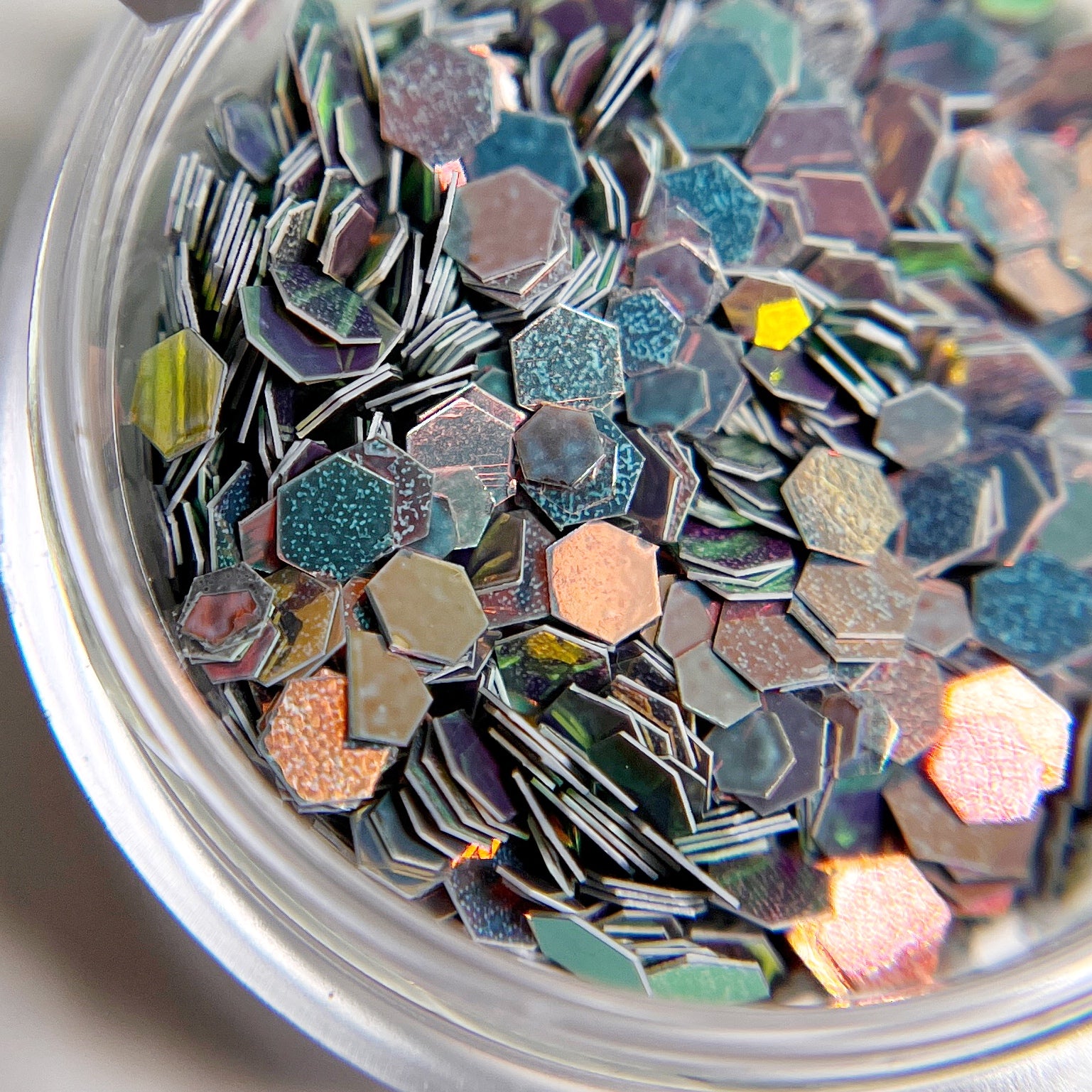 Opalescent gray hexagon glitter mix in clear jar. 