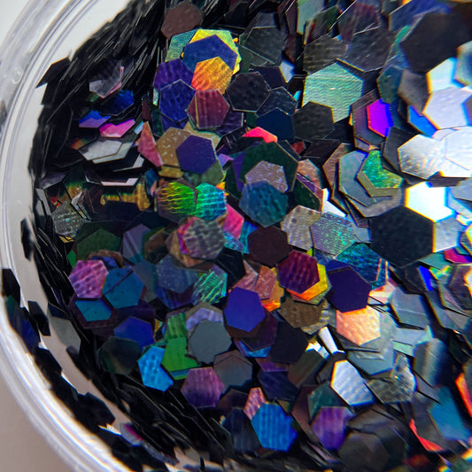 Close up of black duochromatic multi size hexagon glitter. 