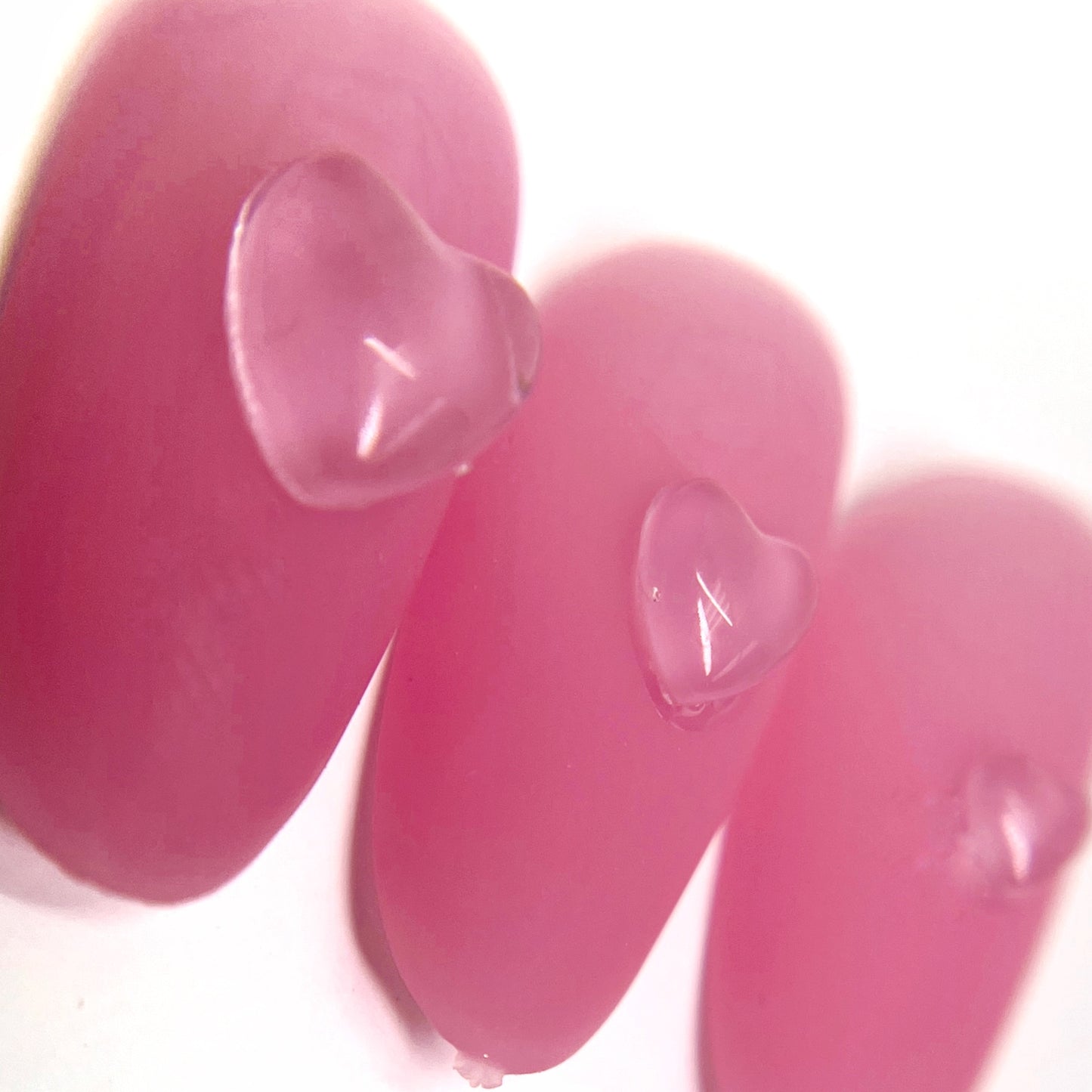 Detail view of pink nail tips with clear heart charms