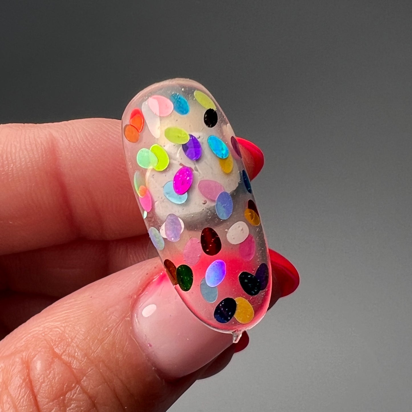 Hand holding decorated nail tip. 