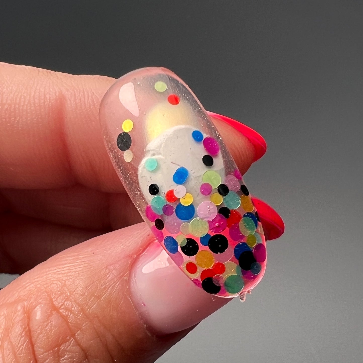 Hand holding decorated nail tip. 