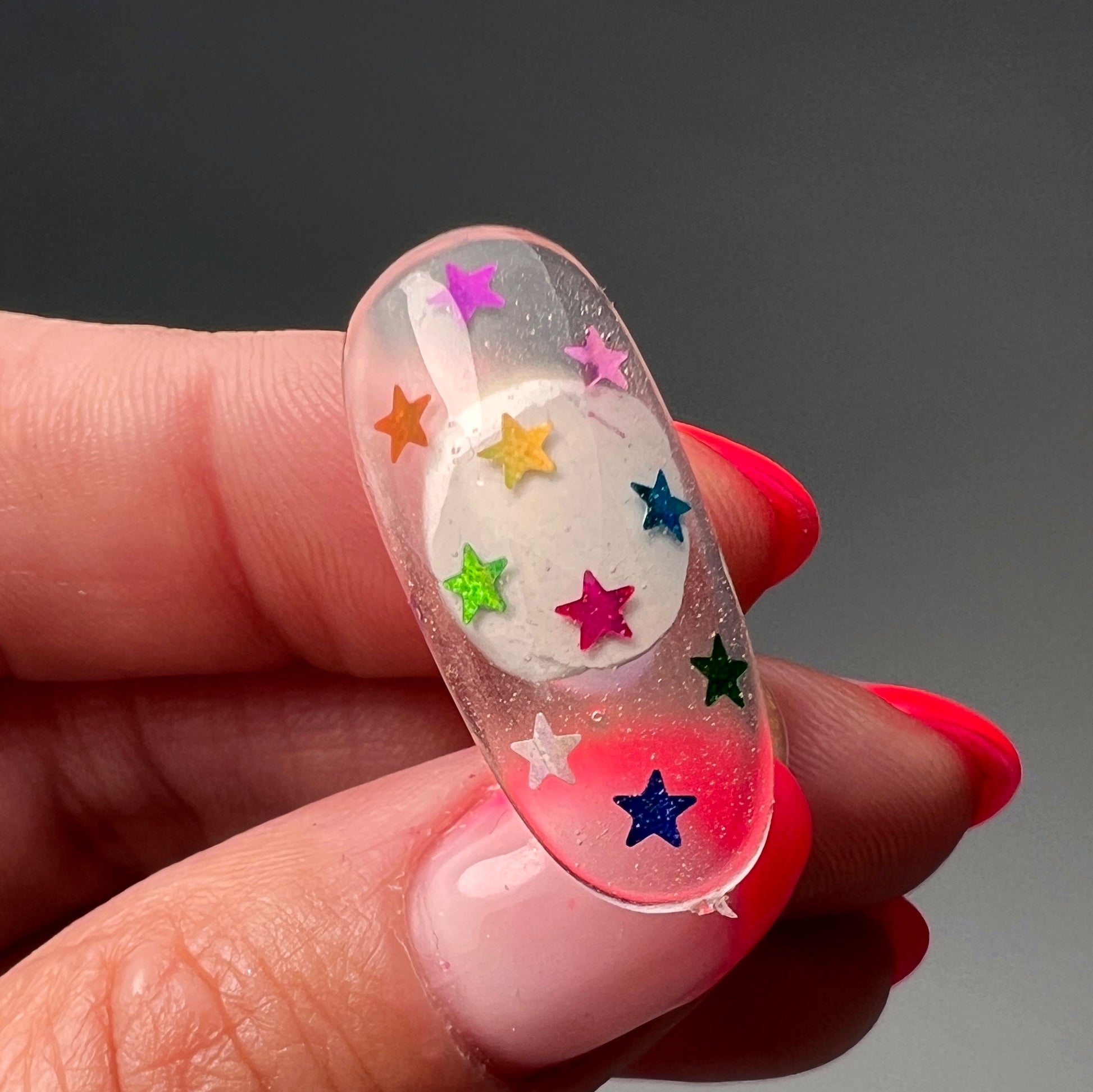 Hand holding decorated nail tip. 