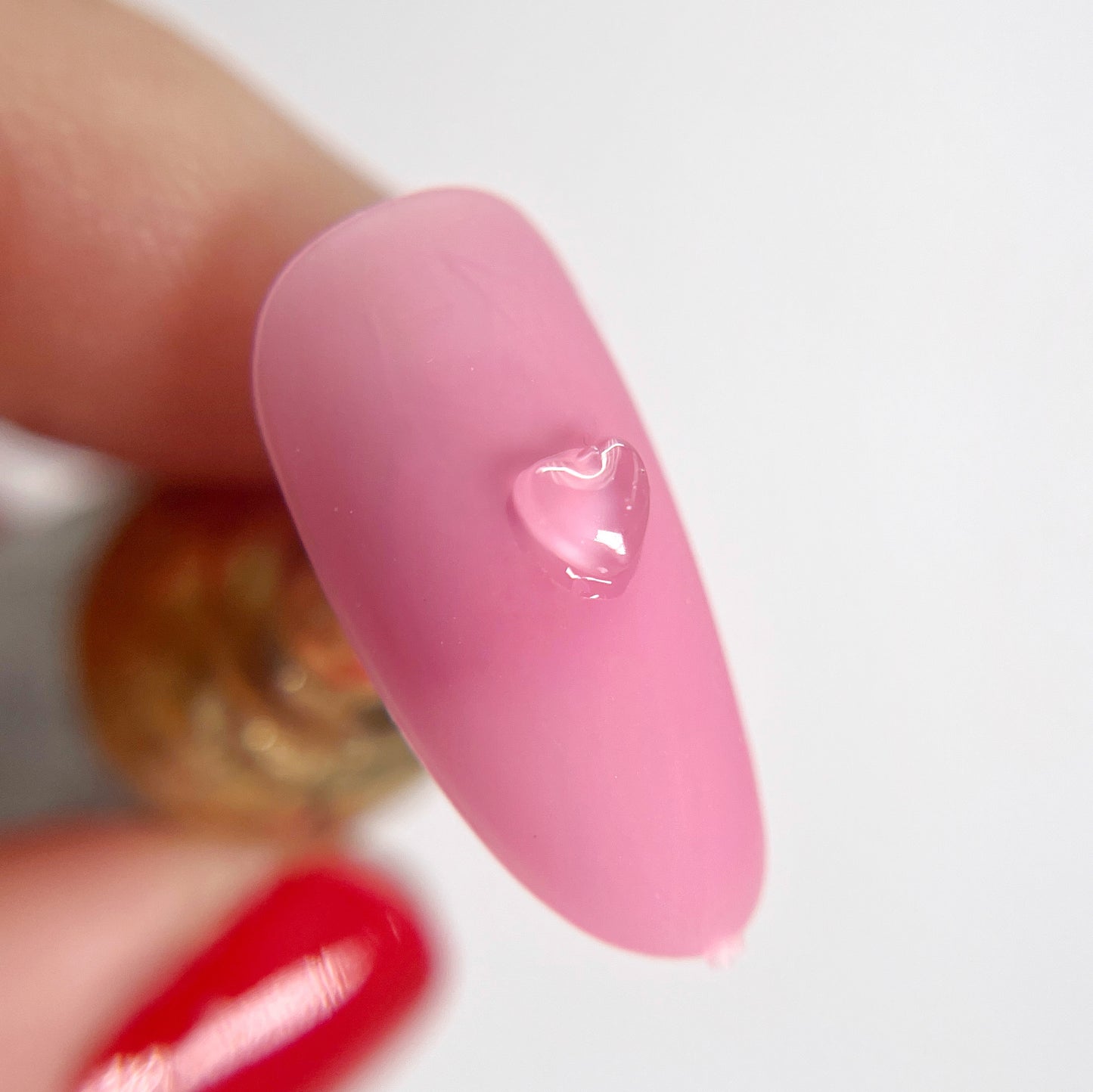 Detail view of pink nail tips with clear heart charms