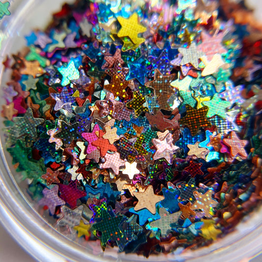 Close uo of multicolor star shaped glitter i clear jar on white background. 