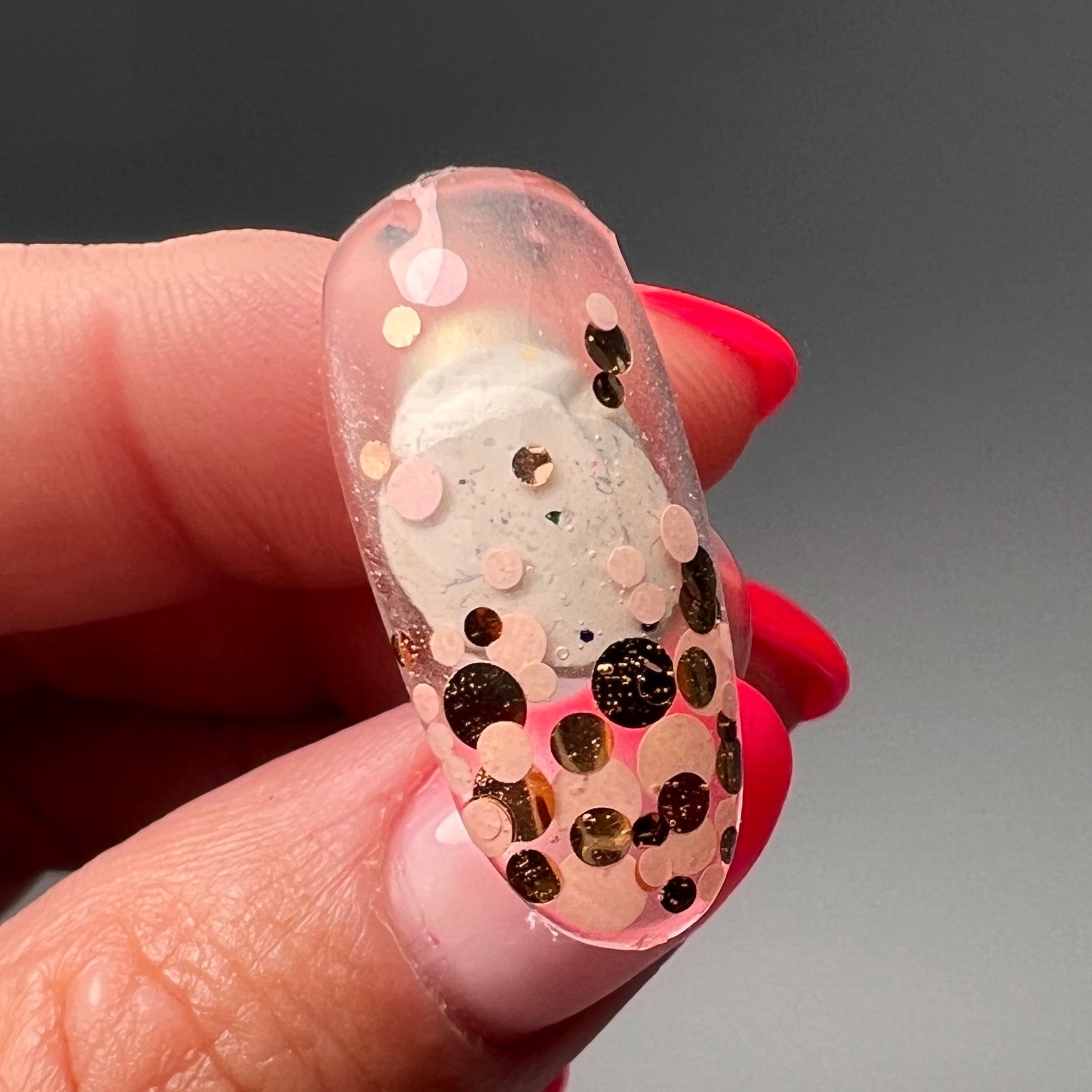 Hand holding decorated nail tip. 