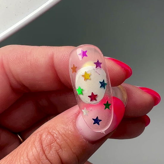 Hand holding decorated nail tip. 