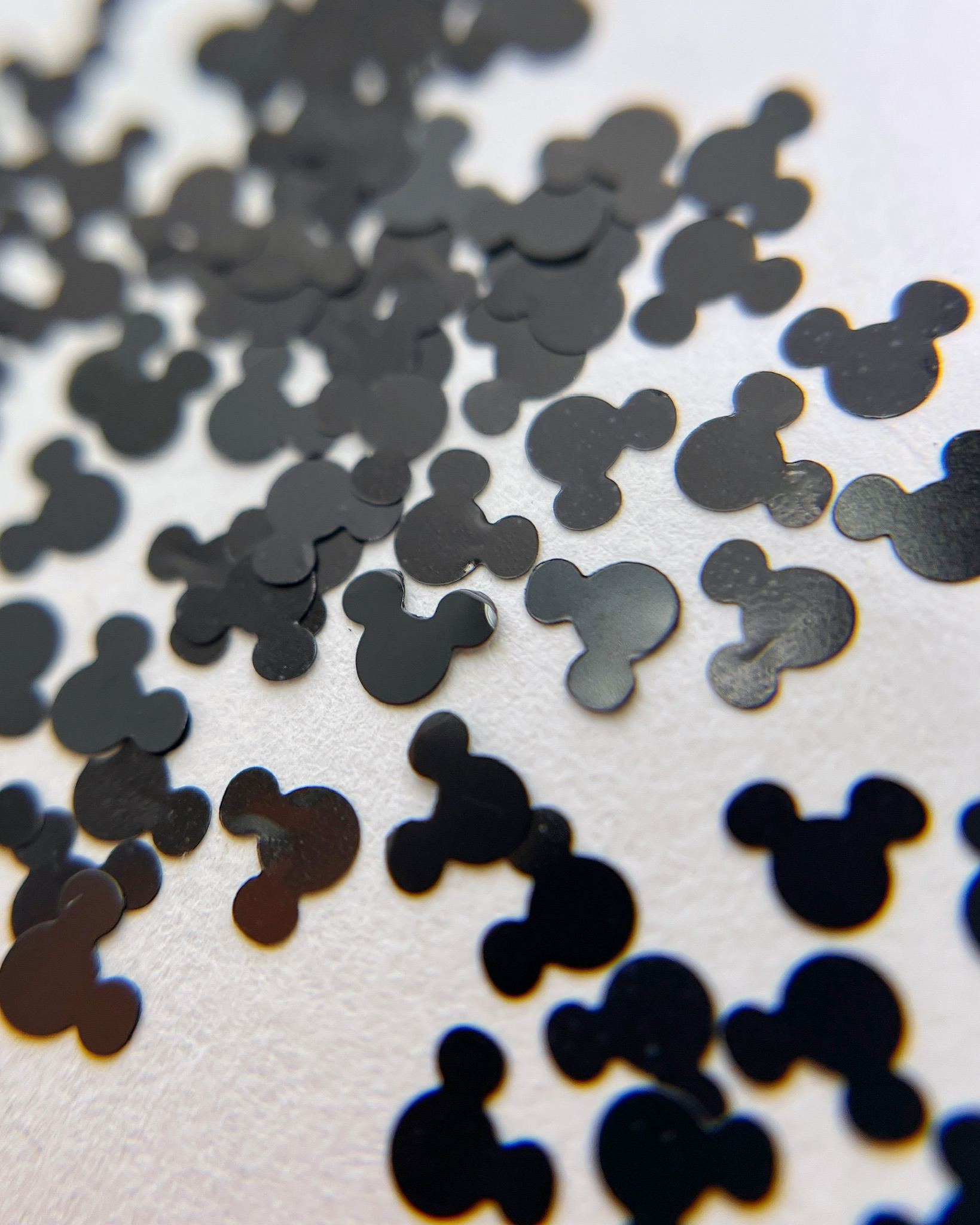 Black mouse sha[ed glitter scattered on a white background. 