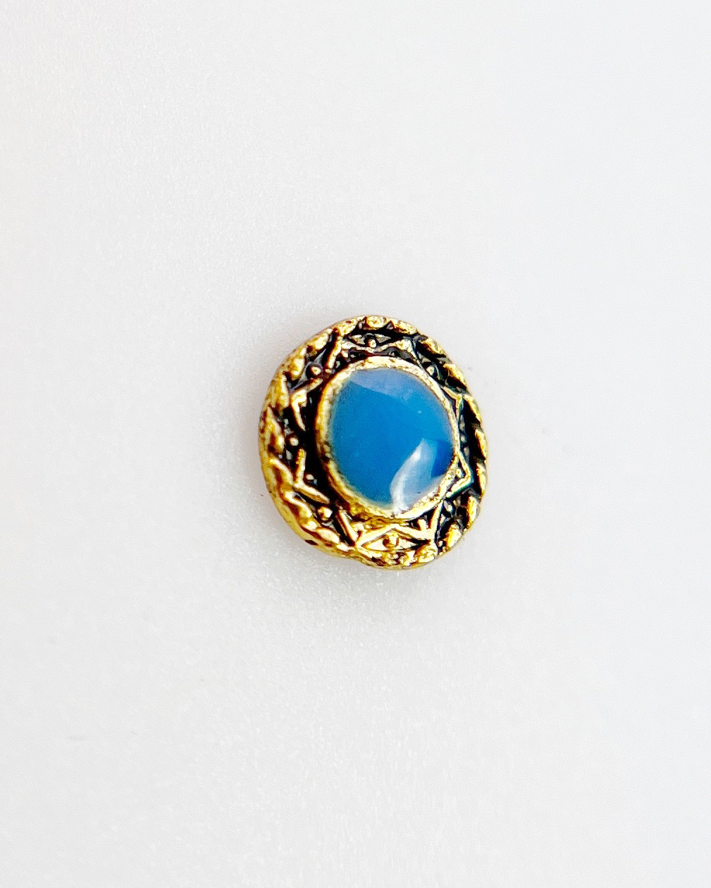 Gold and blue round charm on white background. 