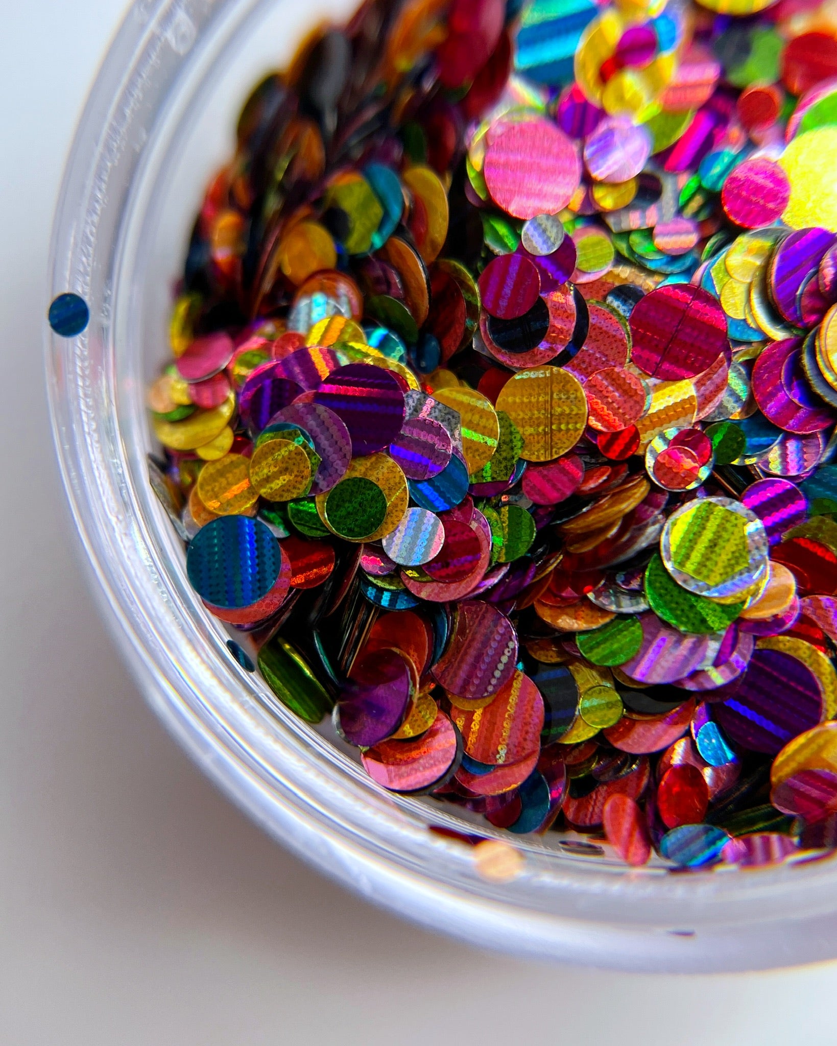 Multicolor glitter mix in clear jar on white background. 