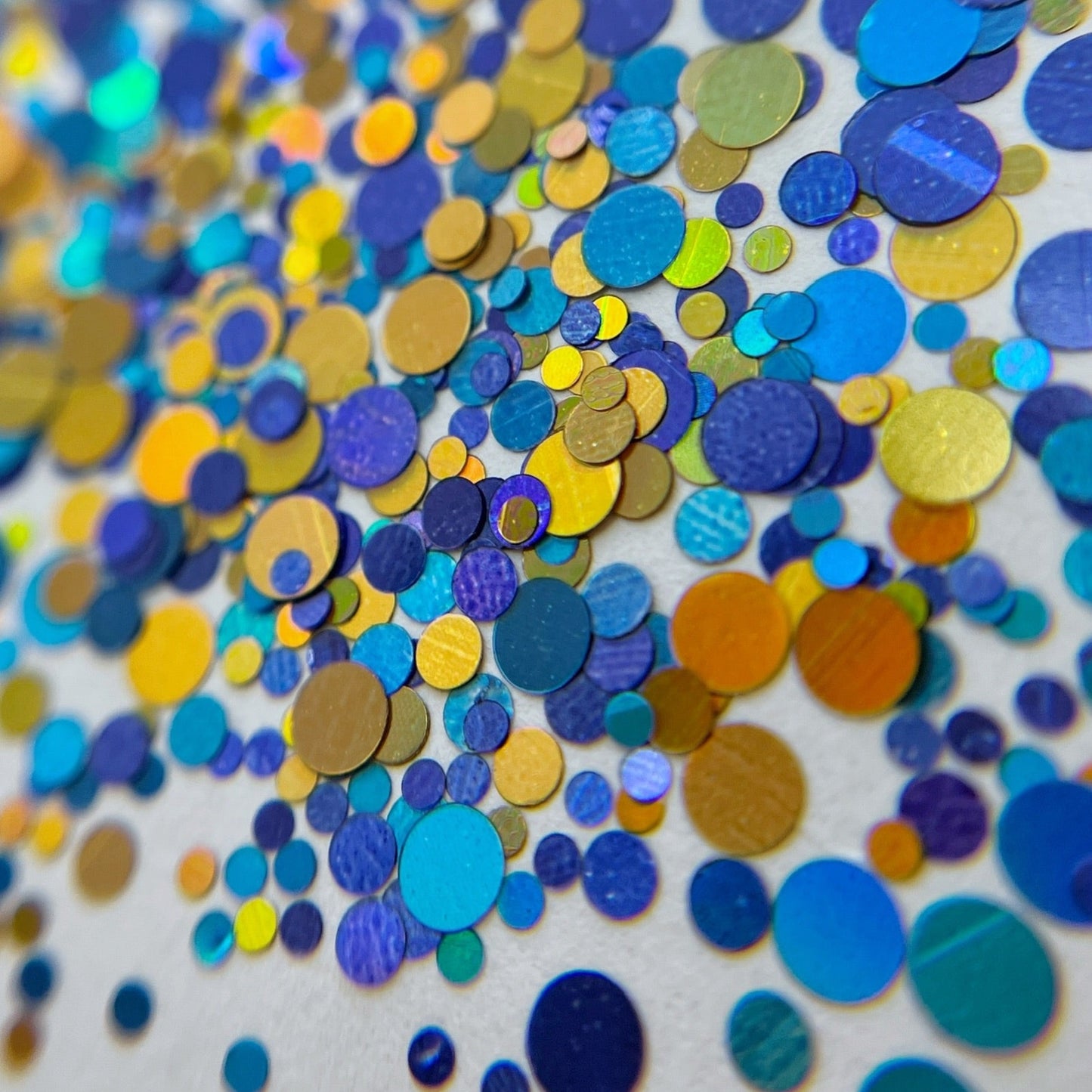 Multicolor round glitter in blue and gold colors scattered on a white background. 