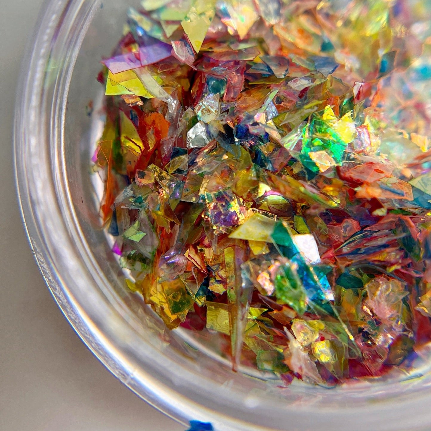 Green tinted multicolor mylar shreds in clear jar on white background.