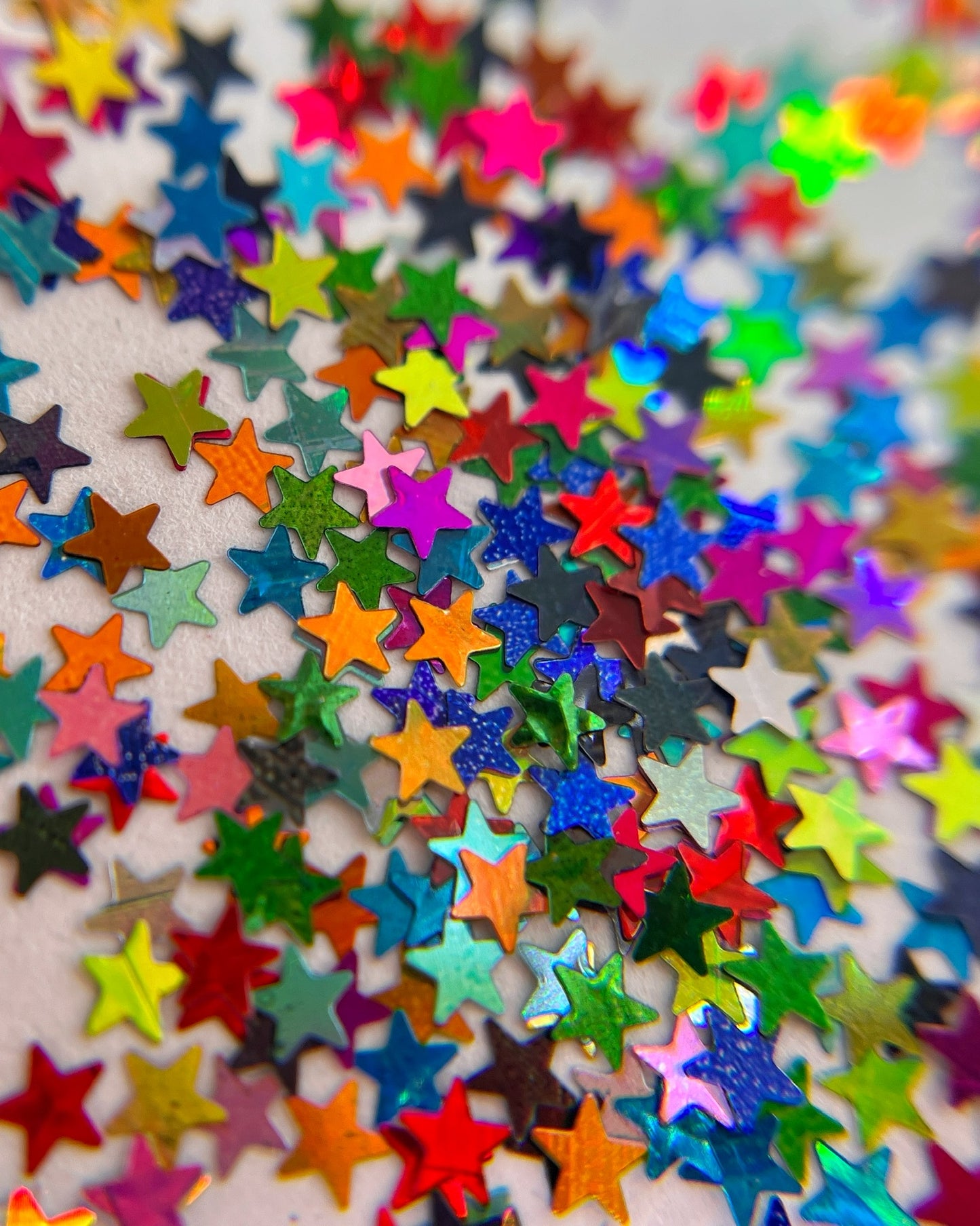 Multicolor star shape glitter scattered  on whte background. 