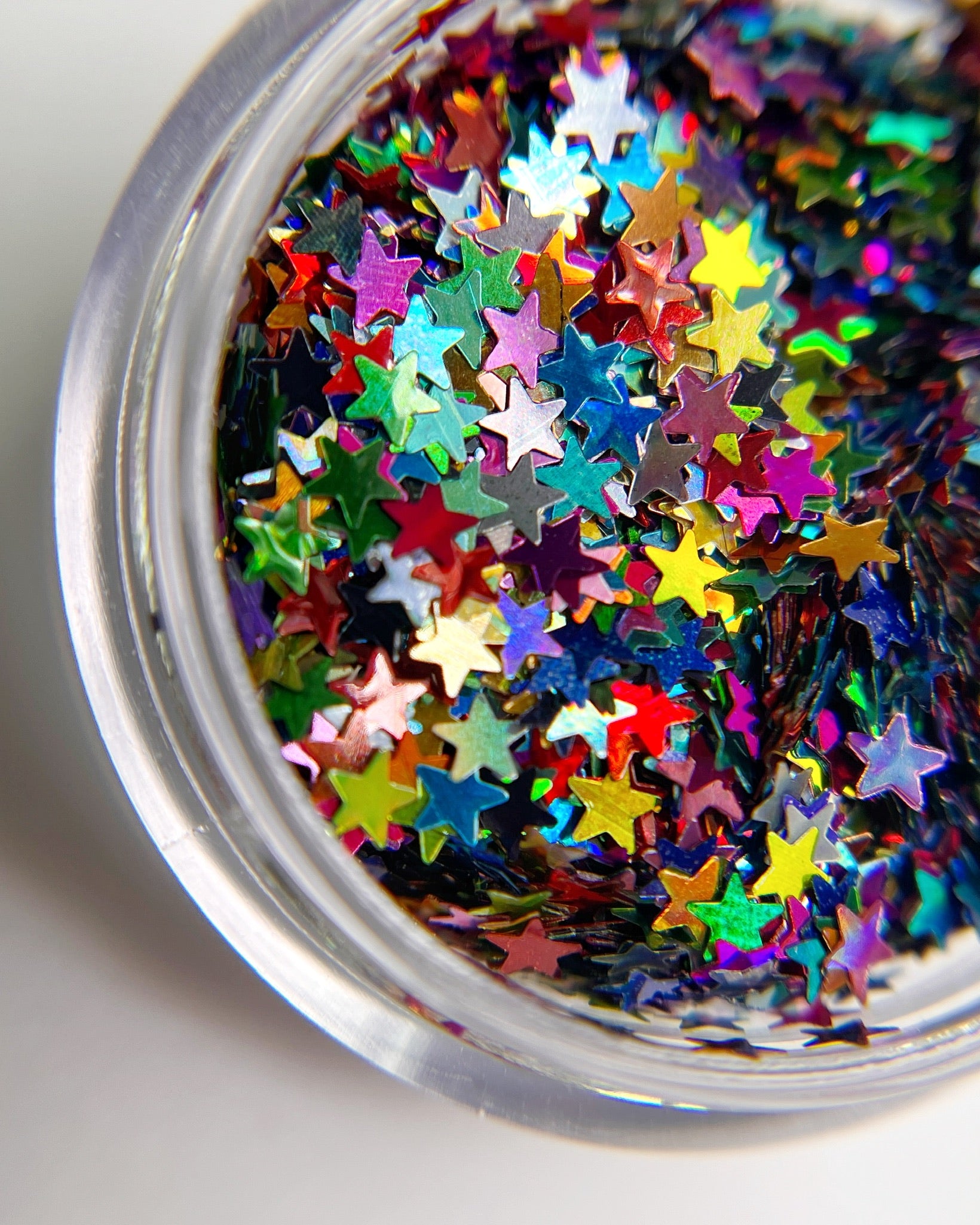 Multicolor star shape glitter in clear jar on whte background. 