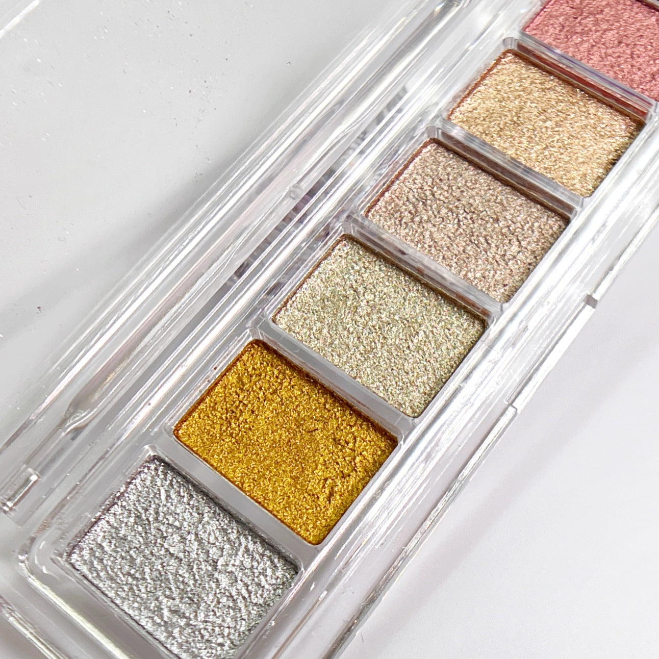 Six color metallic pigment palette in clear container on white background. 