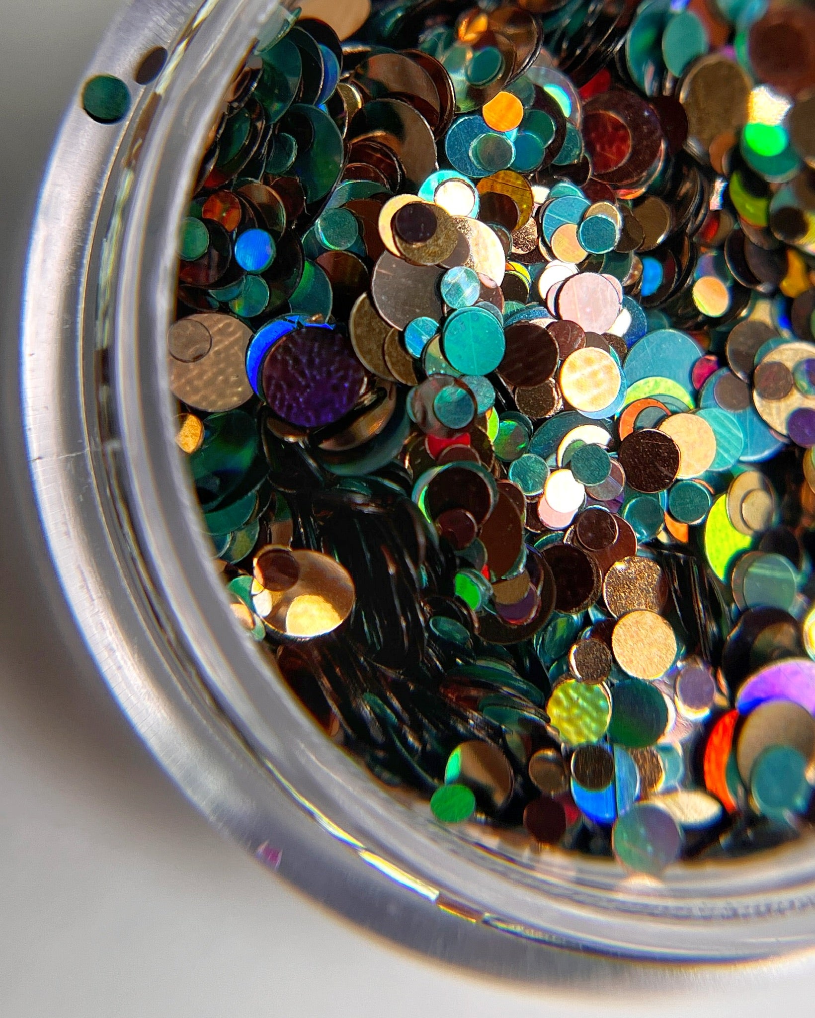 Multicolor circle glitter mix in clear jar on white background. 